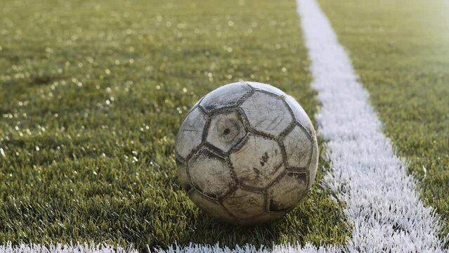 Old ball lies on football field in corner of white lines, close-up.