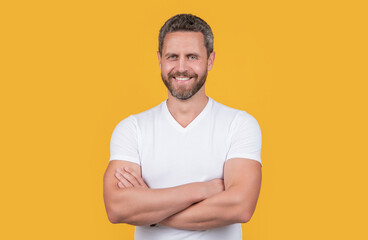 Happy man. Grizzled man smiling in casual white tshirt. Handsome man keeping arms crossed