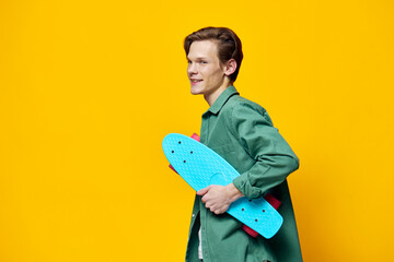 happy man with a blue skateboard in his hands stands sideways to the camera