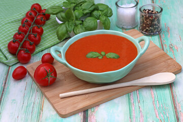 Tomatensuppe mit Tomaten und Basilikum auf einem Holzbrett.