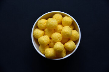 Corn salted and peppered chips on a white plate. Delicious breakfast of corn chips on a black background.