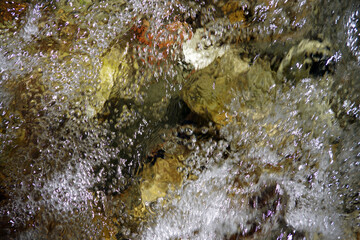 Wild clear and clean creek water flowing and bubbling over rocks