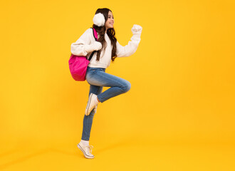 Autumn school. Teenager school girl with backpack in autumn clothes on yellow isolated studio background. Jump and run, jumping kids.