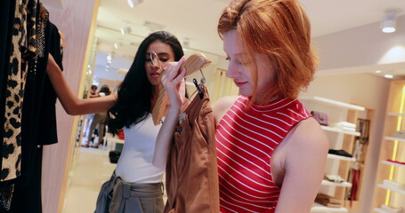 Two young women shopping for clothes at store boutique