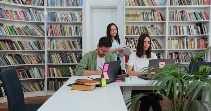 Students have discussion, use laptop, prepare for exams together, helping, researching subjects for the paper assignment. University library.