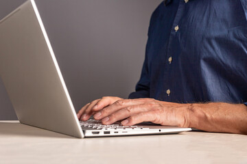 Man hands at laptop keyboard. Male typing email or document text for work or study, surfing Internet while sitting at table with computer. Human chatting with partners, colleagues