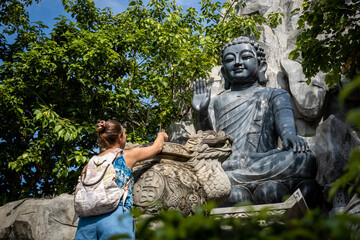 Fototapeta na wymiar Mujer turista dejando incienso a los pies de estatua de buda para su ofrenda