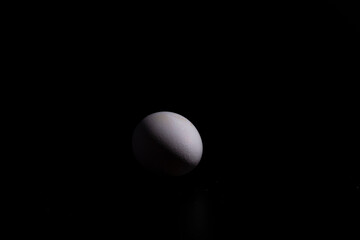 un huevo  blanco de gallina, sobre fondo negro 