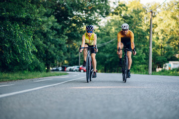 Obraz premium Couple riding road bicycles outside and wearing helmets and sunglasses