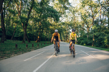 Naklejka premium Couple riding road bicycles outside and wearing helmets and sunglasses