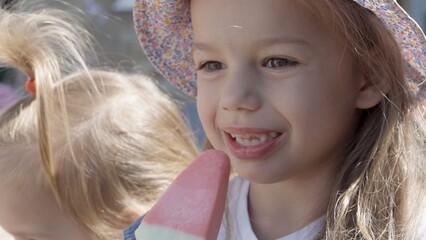 Close up portrait Girl enjoys delicious ice cream cone. Child eating watermelon popsicle. Kids...