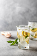 Iced refreshing detox water with lemon, mint in glasses with wooden juicer. Homemade lemonade or cocktail. Copy space