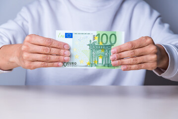 hands holding a one hundred euro bill
