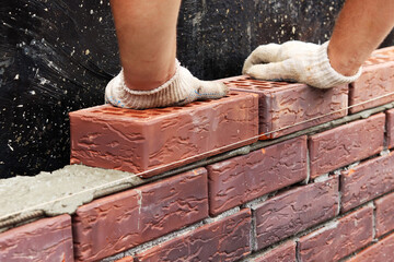 Construction of a brick wall. Bricklaying. A worker builds a brick wall. selective focus