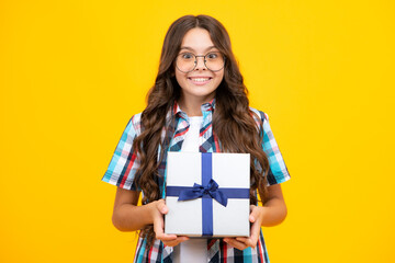 Teenager child holding gift box on yellow isolated background. Gift for kids birthday. Christmas or New Year present box.