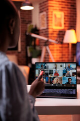 Fototapeta premium Businesswoman chatting with remote team on teleconference using laptop, back view. Company colleagues discussing business on videocall, office employees teamwork and cooperation
