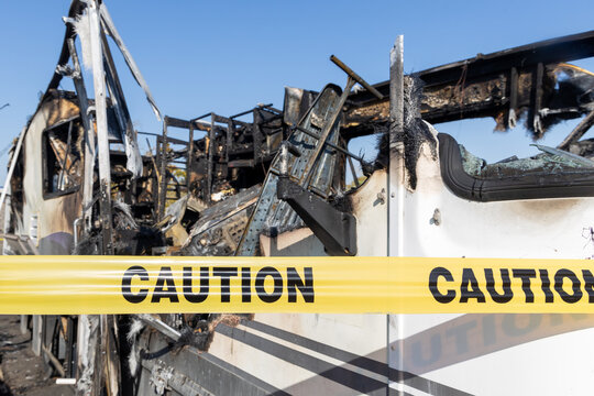 Burned out RV motorhome interior from a fire or explosion or fire bomb or arson shows the melted interior and the devastation of the accident.  Yellow caution tape,