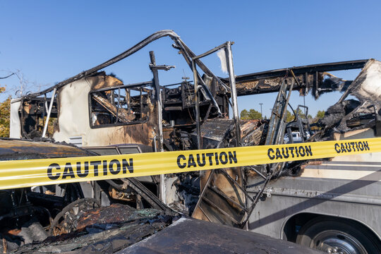 Burned out RV motorhome interior from a fire or explosion or fire bomb or arson shows the melted interior and the devastation of the accident.  Yellow caution tape after the fire is out.  