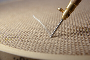 Punch needle with a burlap fabric in a embroidery hoop and a threaded needle with a woolen thread