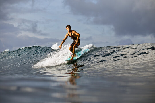 Man surfing in sea against cloudy sky