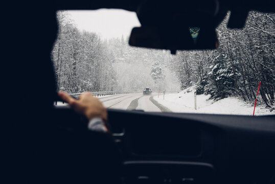 Cropped image of person driving car on snow covered road