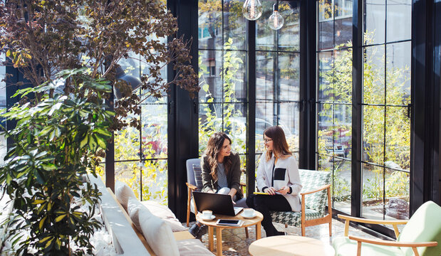 Businesswoman using laptop computer with colleague in cafe