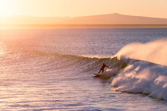 Man surfing in sea against sky during sunset