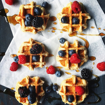 Overhead view of berry fruits and honey garnished on waffle at table