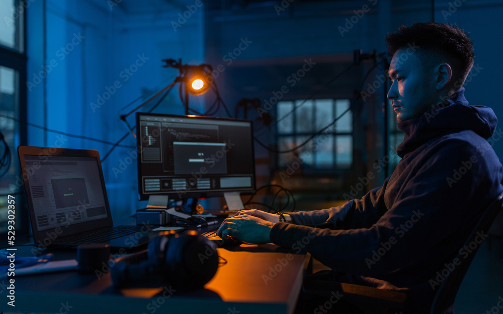 Poster cybercrime, hacking and technology concept - male hacker in dark room writing code or using computer