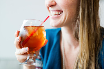 Midsection of smiling woman enjoying ice tea in cafe