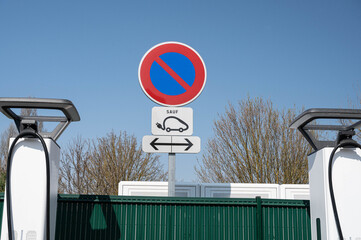 Close-up of a no-parking sign and a pictogram of an electric car at an electric charging station.