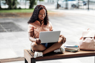 technology, education and people concept - happy smiling african american student girl with laptop computer and books in city