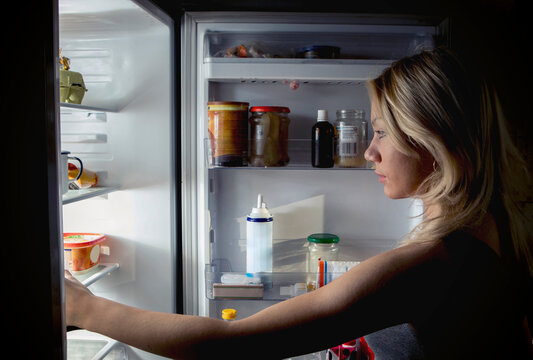Close-up of teenage girl searching food in refrigerator at kitchen