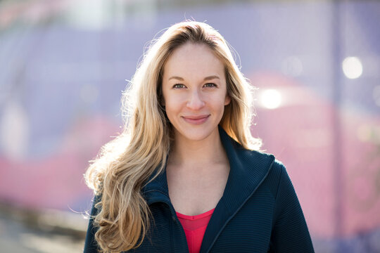 Close-up Portrait Of Confident Athlete Standing By Fence During Sunny Day