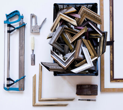 Overhead view of picture frames and corners with work tools on table in workshop