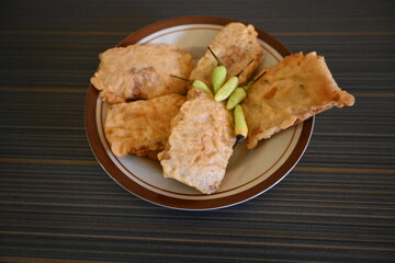 Fried tempeh (gorengan) is a very popular favorite food in Indonesia. Fried tempeh is served in a plate and sprinkled with green cayenne pepper on top