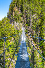 Simple suspension footbridge over mountain valley