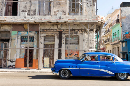 Man riding car on street by abandoned building in city