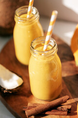 Pumpkin and coconut smoothie with cinnamon in bottles with straw. Healthy raw vegan food. Closeup