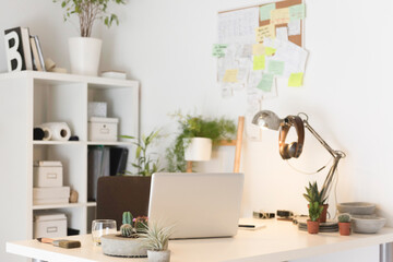 Laptop computer on desk with lamp houseplants in creative office