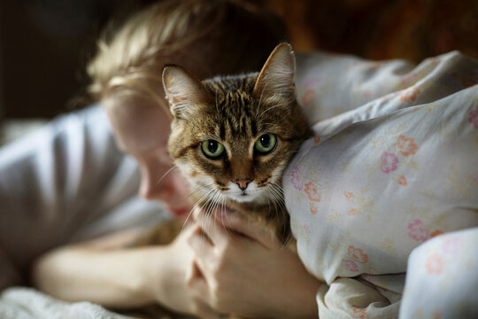 Woman embracing cat while lying on bed at home