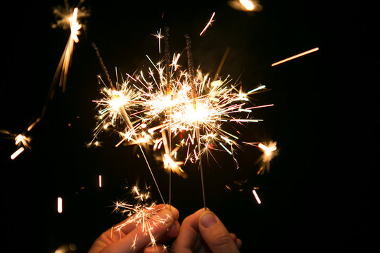 Cropped hands of woman holding sparklers
