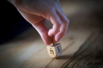 Cropped hand of man spinning dreidel on table