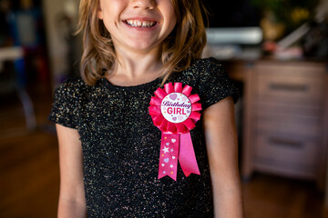 Midsection of happy girl with birthday badge at home