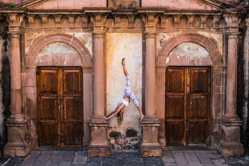Woman practicing yoga on architectural columns of old building