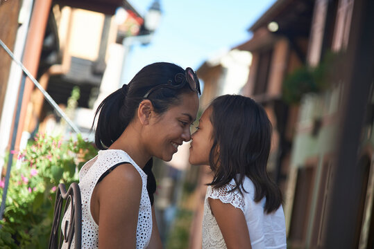Side view of mother and daughter rubbing noses in city
