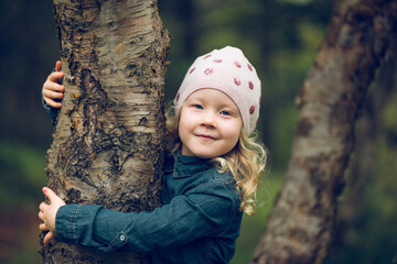 Portrait of cute girl embracing tree trunk at park
