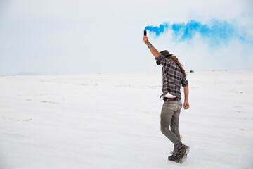 Side view of man holding smoke bomb while standing on Bonneville Salt Flats against sky