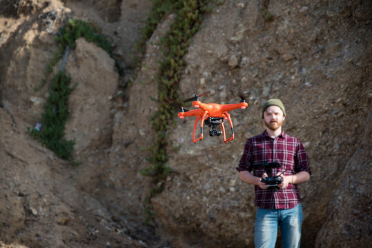 Man flying drone while standing against rock formation