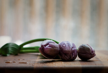 Close-up of wet purple tulips on wooden table